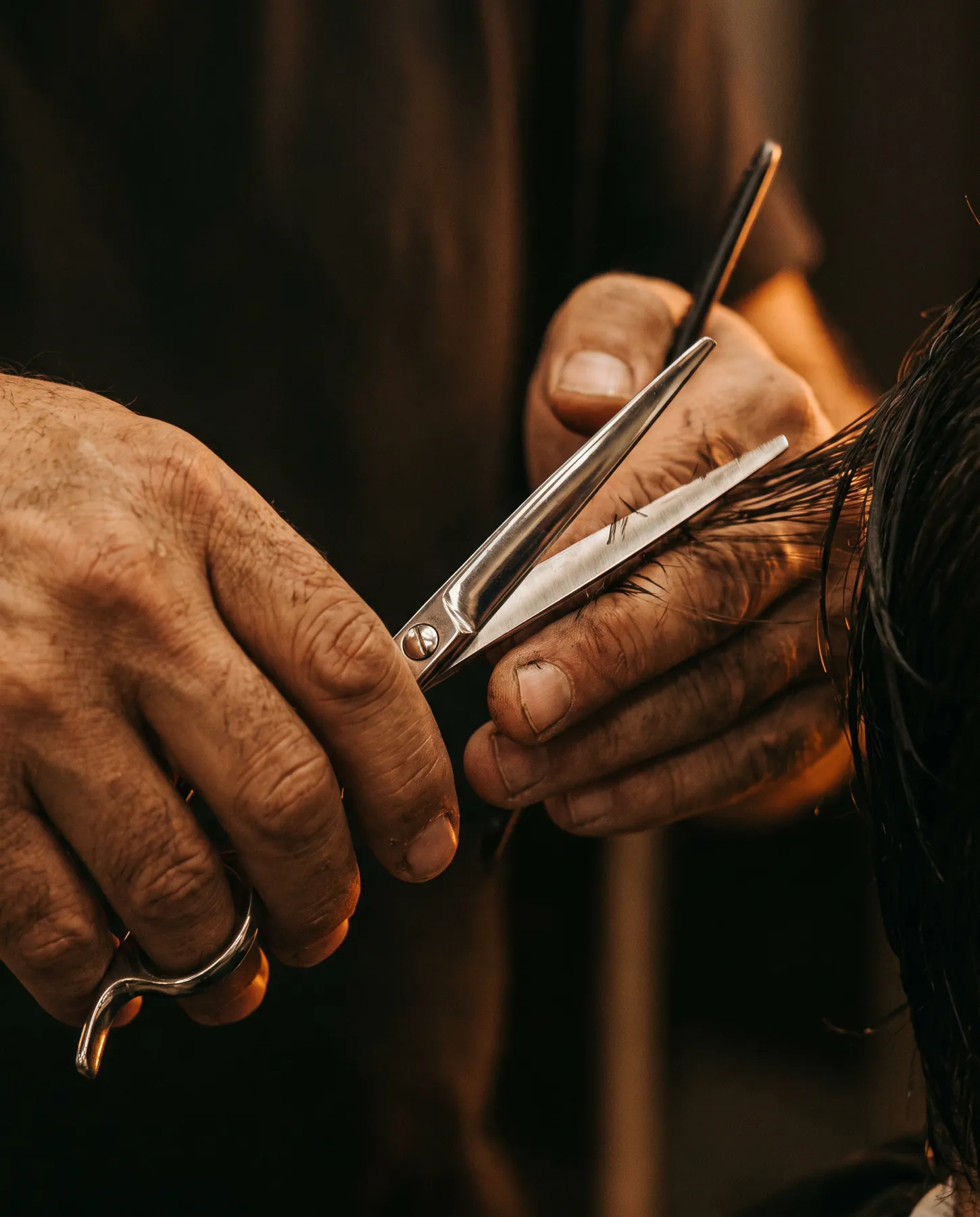 Close detail of a barber cutting hair with steel scissors