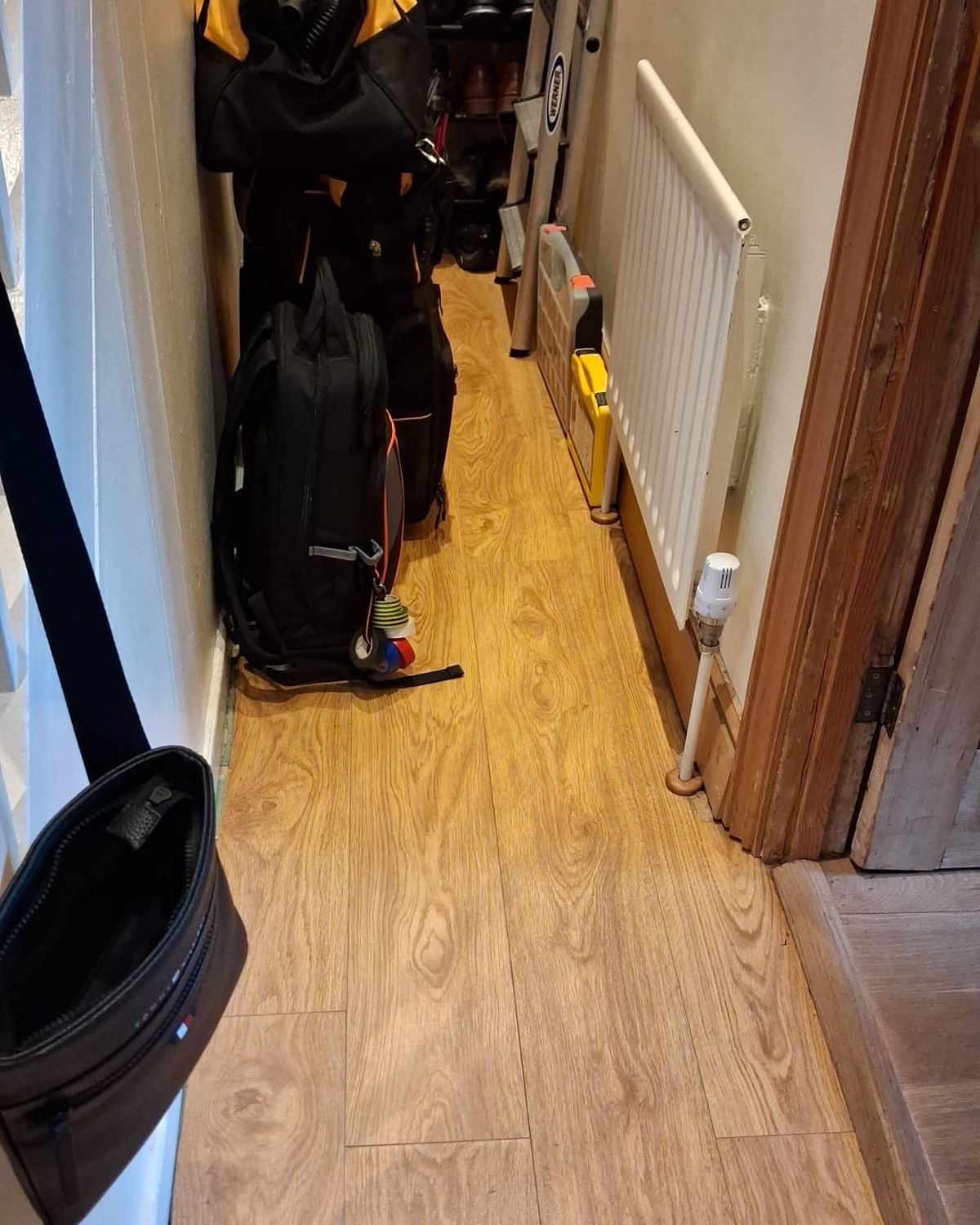 Before: a narrow hallway with a laminate floor, bags and a shoe rack