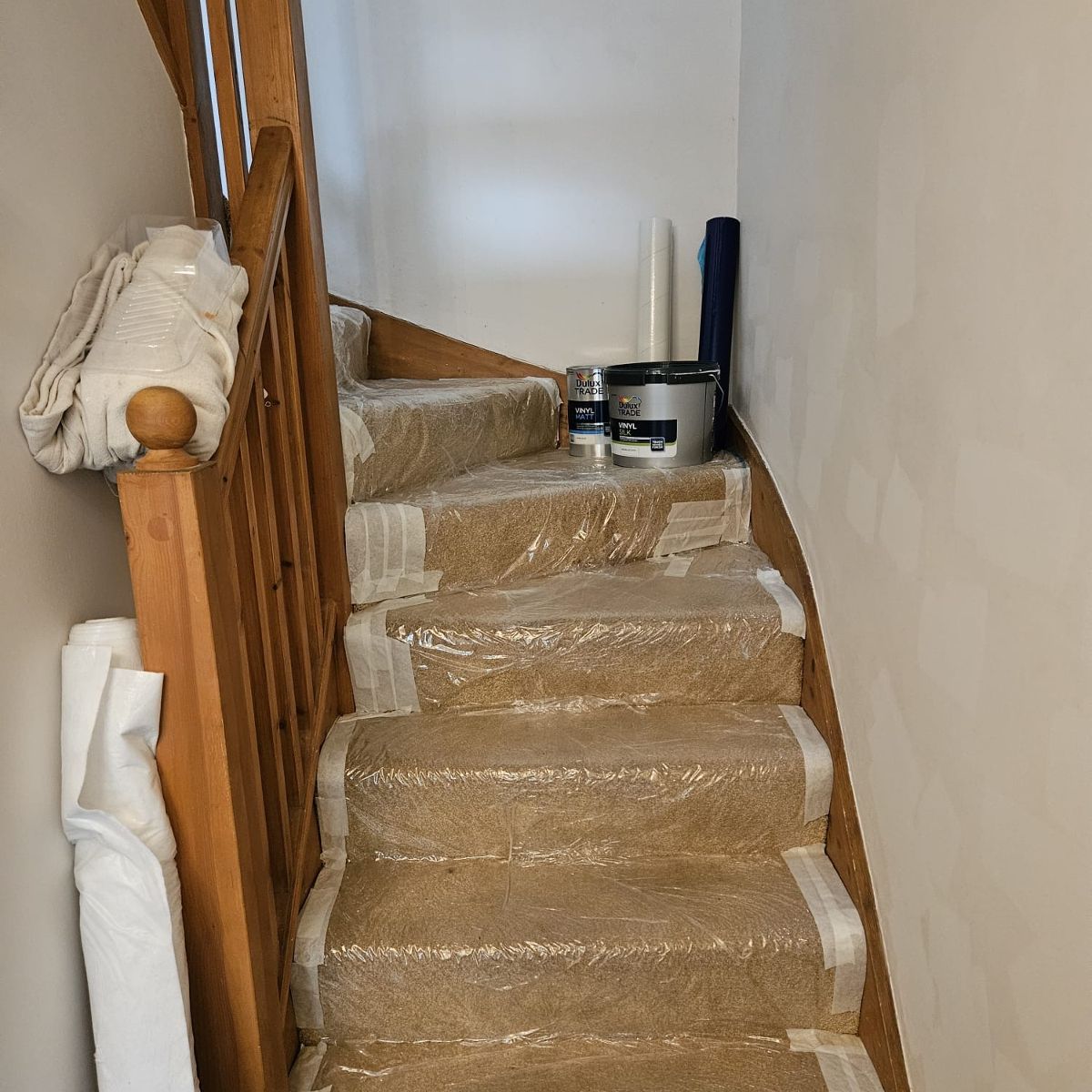 Before: the stairwell sheeted up, walls stripped back ready for paint