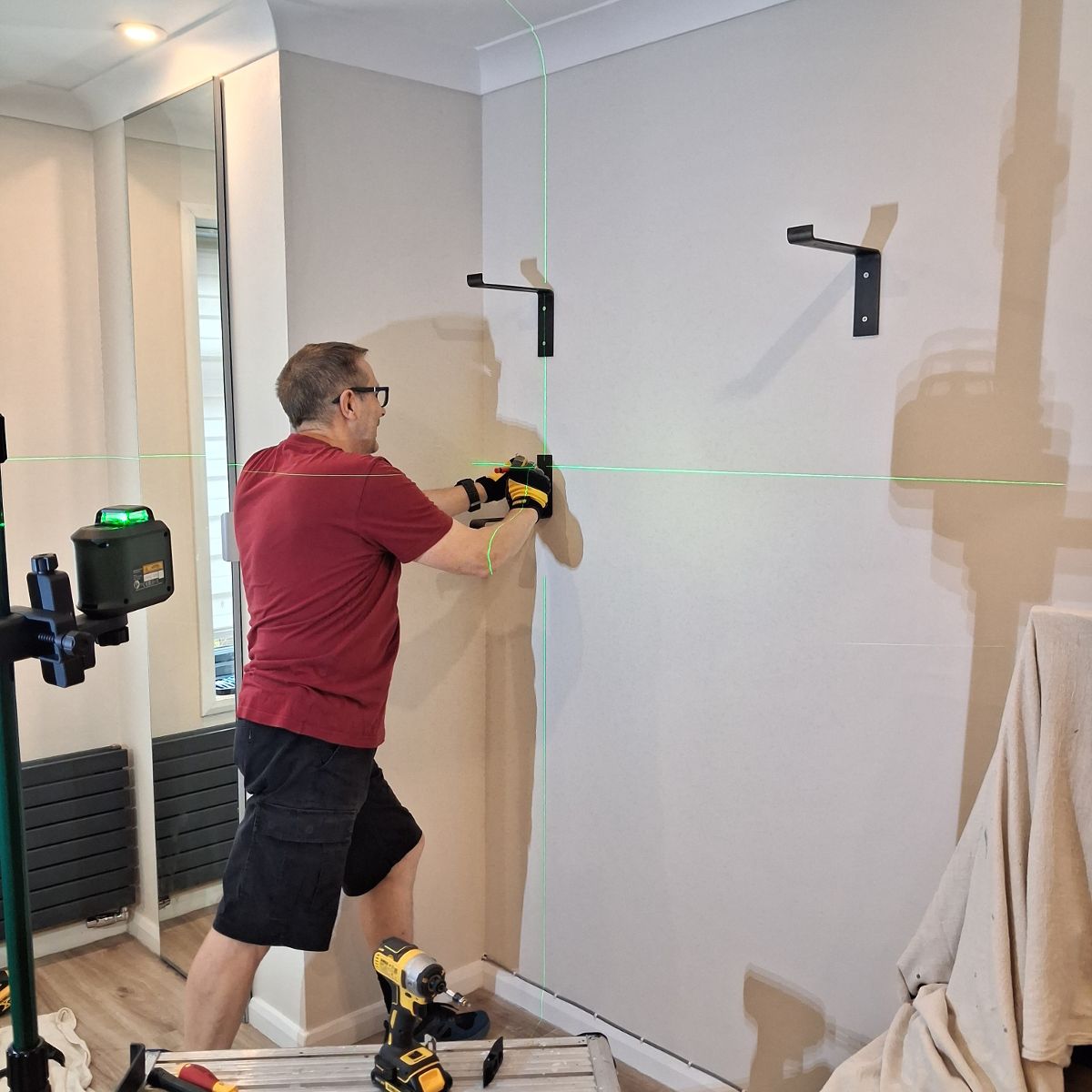 Before: brackets fixed to the wall against a laser line