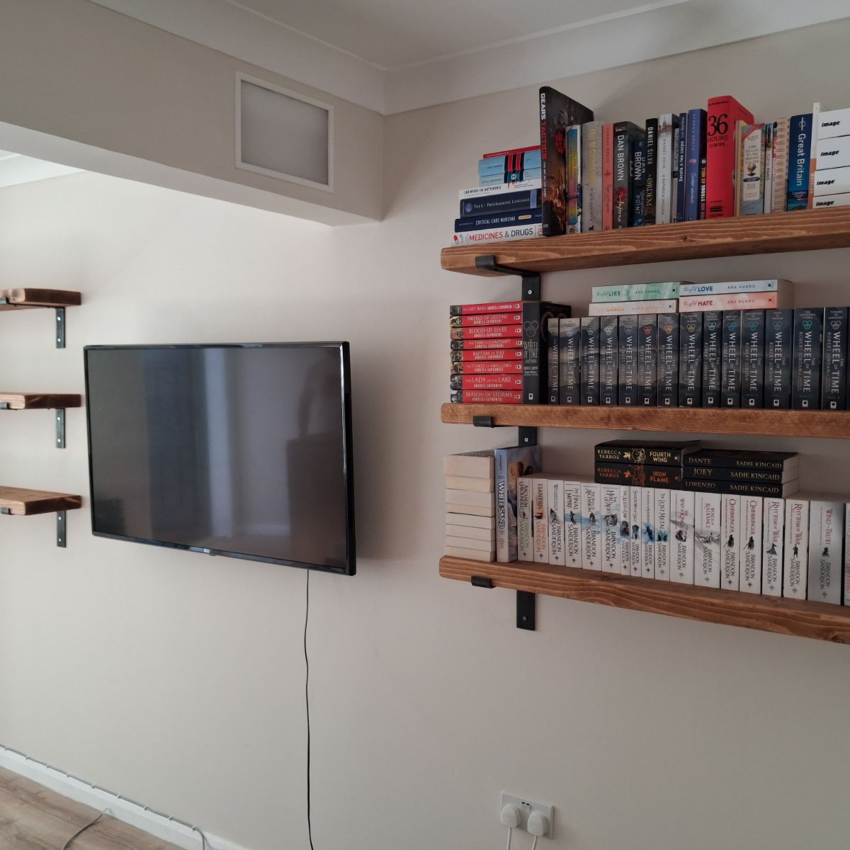 After: the television mounted on the wall with three loaded bookshelves beside it